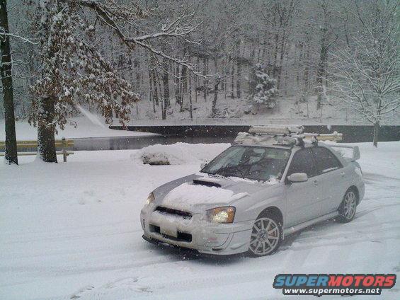 Silver Subaru Impreza WRX with roof rack in snow. Hood scoop visible