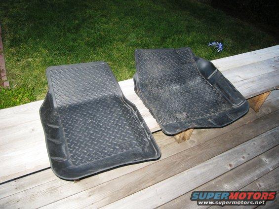 Two black diamond-tread rubber floor mats on a wooden deck