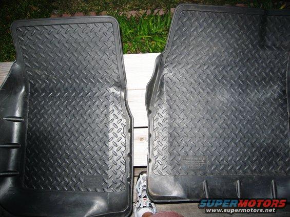 Two black rubber floor mats with diamond tread pattern, one partially obscuring the other