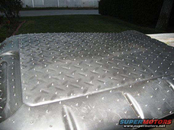 Diamond plate floor mat with raised spikes, possibly for a vehicle