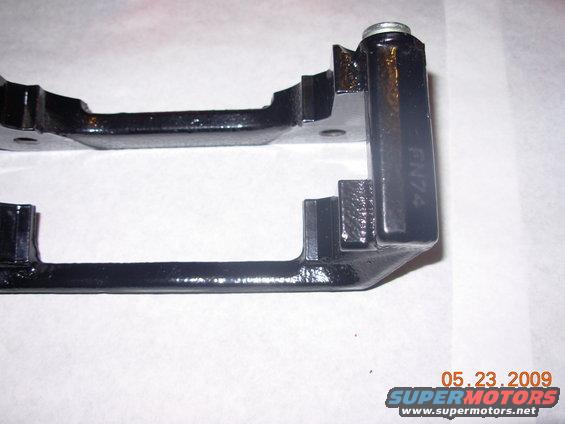 Black brake caliper bracket with "GN74" stamped on the side