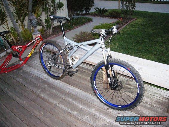 Two mountain bikes, one silver and one red frame, on a wooden deck