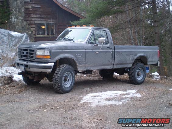 Gray Ford F-350 pickup truck parked in front of a log cabin