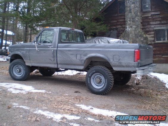 Gray pickup truck, side view, with a covered object in the bed
