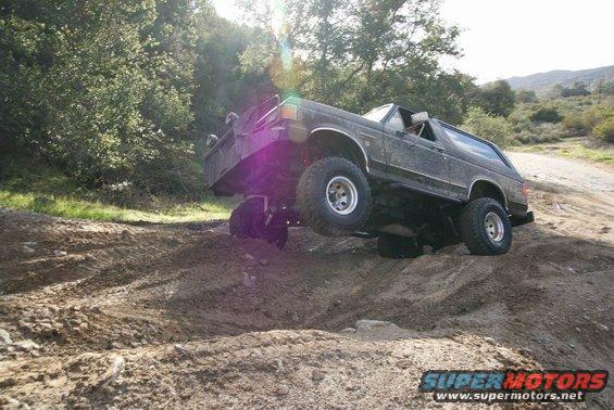 1991 Ford Bronco climbing a dirt hill with front wheels off the ground