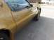 1978 Pontiac Trans Am - A gold vehicle is seen from the side, parked on a paved surface with some background blur.