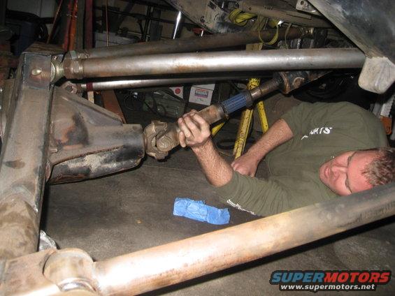 Mechanic lying down, working on a vehicle's driveshaft and differential