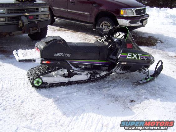 Black 1990 Arctic Cat El Tigre EXT snowmobile with green and purple stripes, parked in snow