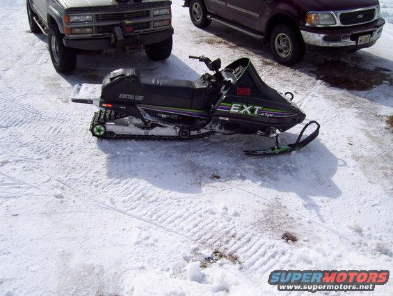 Black Arctic Cat El Tigre EXT snowmobile with green and purple stripes parked in snow