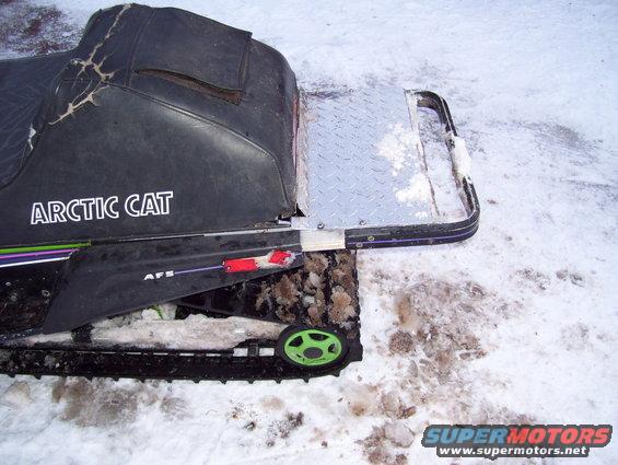 Arctic Cat snowmobile rear section with cracked black seat and diamond plate cargo rack