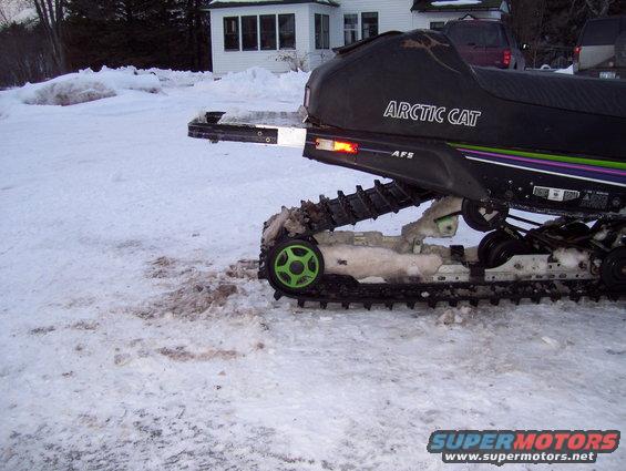 Rear view of an Arctic Cat snowmobile with a black seat and green track wheels