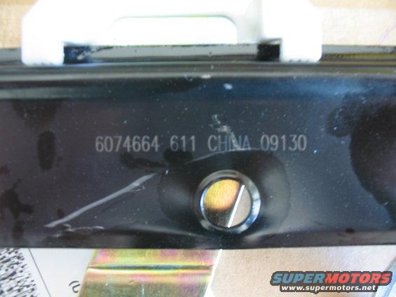 Black metal part with stamped numbers 6074664 611 CHINA 09130 and a circular fastener
