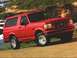 1996 Ford Bronco - This red Ford Bronco is parked on a dirt road with some rocks and vegetation in the background.