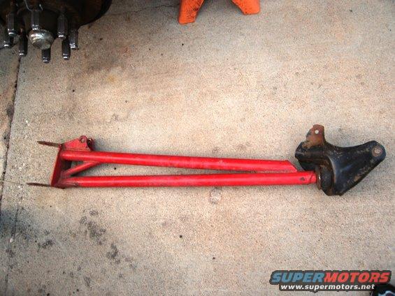 Red radius arm assembly with black bracket on concrete