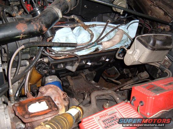 I used the cardboard to mark and drill the outermost bolt holes. Then I made relief cuts along the bottom to clear the head bolts and spark plugs. Straight cuts got most of it but I cut wider angled slots to get at least 1/8" around the ends of the spark plug boots.