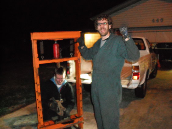 Two guys with a hydraulic press and a pickup truck in the driveway at night