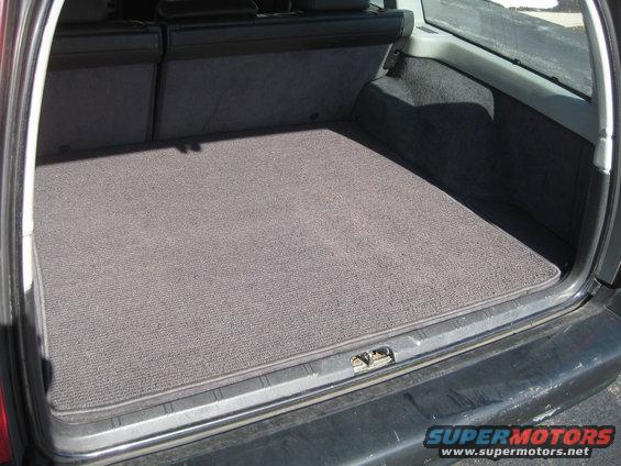 Trunk interior with gray carpet mat and folded rear seats