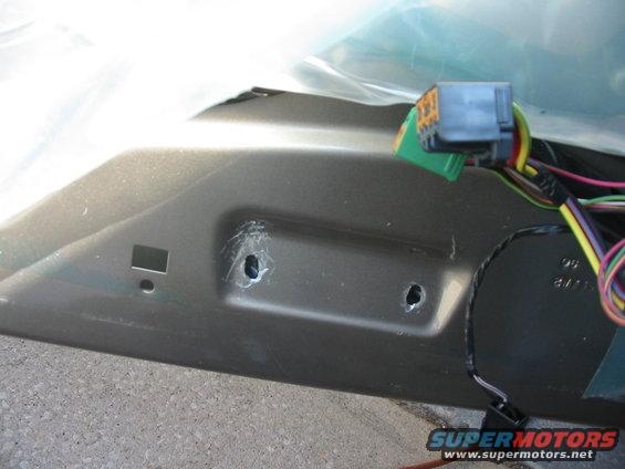 Close-up of car door interior showing wiring harness and connector, with two mounting holes
