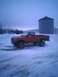 2001 Dodge 2500 - A red pickup truck sits in a snowy landscape next to a large silo and building.