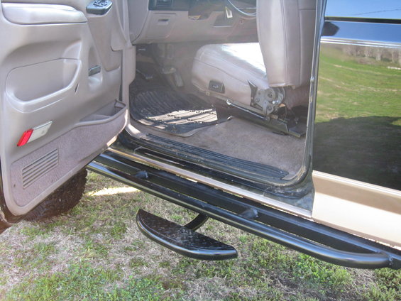 Interior view of a dark-colored SUV with aftermarket side steps and a tan interior