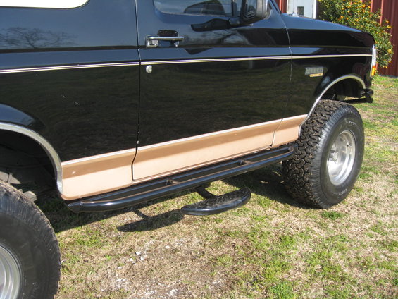Side view of a black Ford Bronco with tan trim and running boards