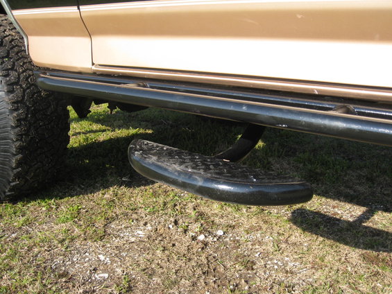 Tan vehicle side with black tubular step and large tire