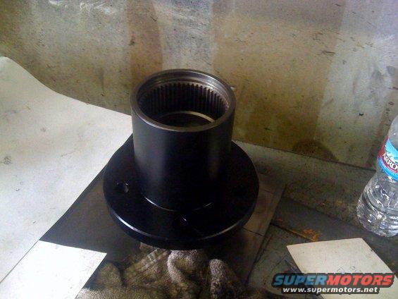 Black metal automotive part with splines inside, on a workbench