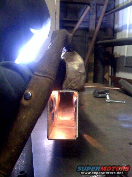 Welder working on a metal tube with holes