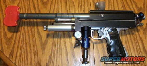 Paintball marker with red handle on barrel, silver and blue air tank, and black grip