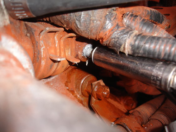 Socket wrench on a rusty engine component with hoses and wiring