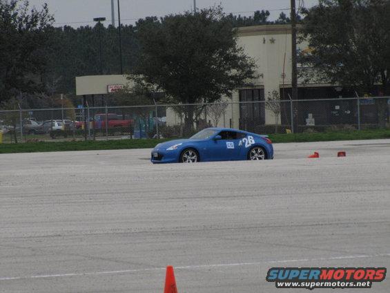 Blue sports car with number 26 on the door, parked on a paved lot