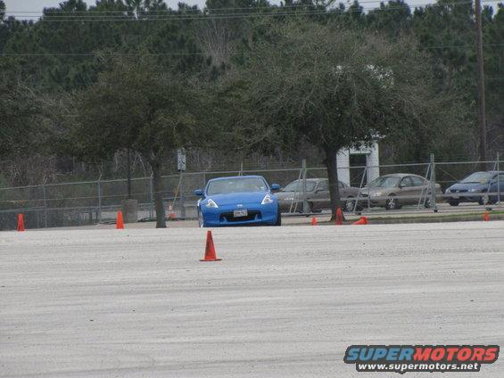 Blue sports car with orange cones on a paved lot