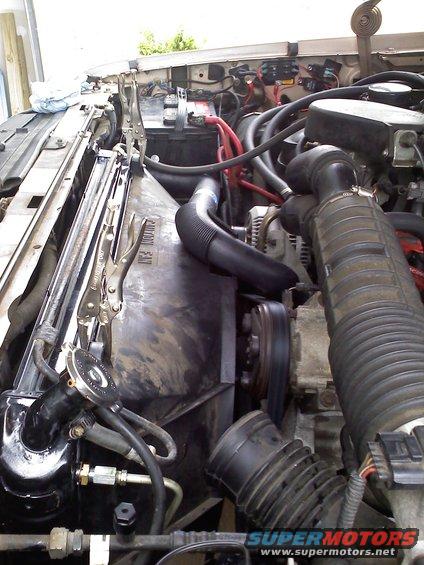 Engine bay with radiator and fan shroud held by clamps