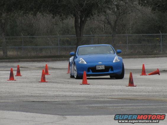 Blue sports car driving through an autocross course with orange cones