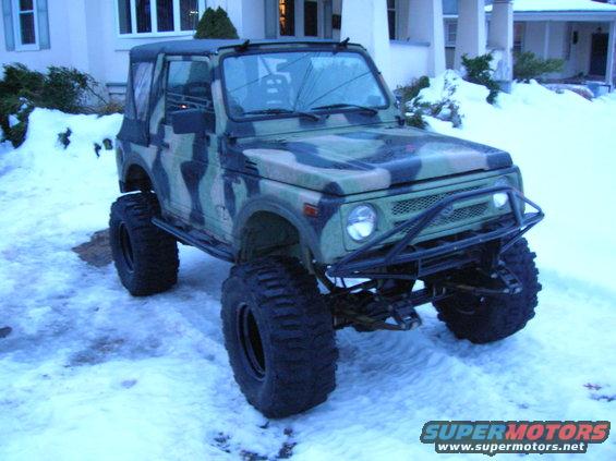 Camouflaged Suzuki Samurai with large tires parked in the snow
