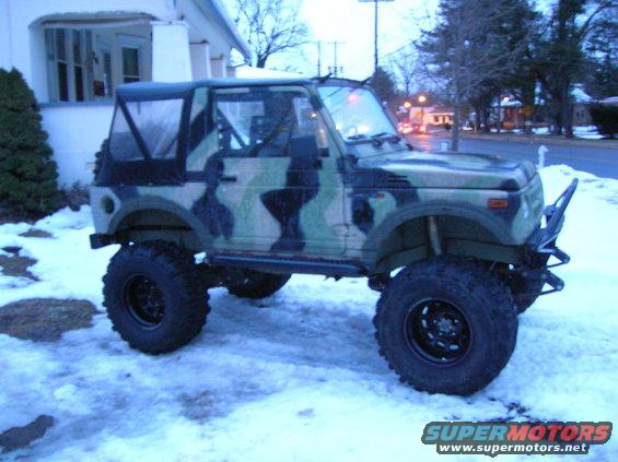 Camouflage Suzuki Samurai with soft top and off-road tires parked in snow