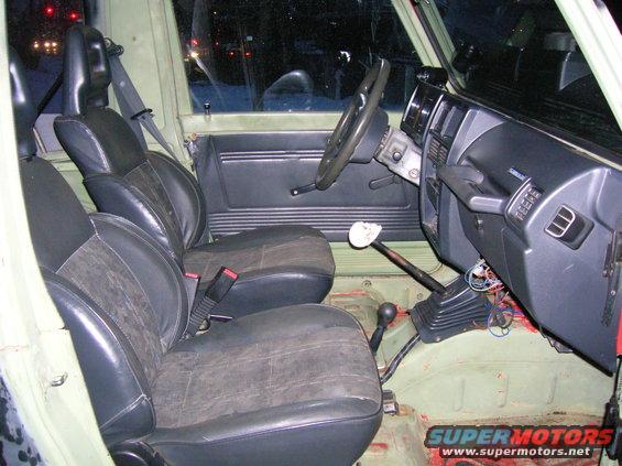 Interior view of a utility vehicle showing front seats, dashboard, steering wheel, and gear shifters