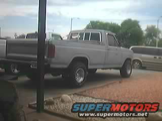Gray Ford F-150 pickup truck, lifted with off-road tires. Another vehicle is partially visible on the left