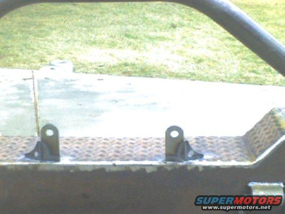 Close-up of custom bumper brackets welded onto diamond plate