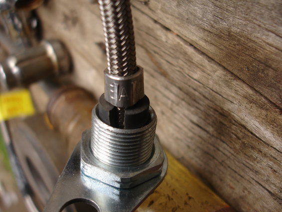 Close-up of a metal braided hose fitting with 'JAE' stamped on the collar