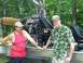 1979 Ford F-250 - Two men stand next to an airboat, which is equipped with a large propeller and engine, in a wooded area.