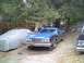 1973 Ford Ranchero - A blue pickup truck is parked on blocks in a yard with trees and other vehicles present.