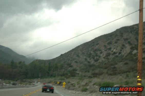 Car driving on a highway through a mountainous area under a cloudy sky