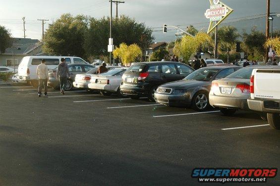 Cars parked in a lot, with a Mexican food sign in the background