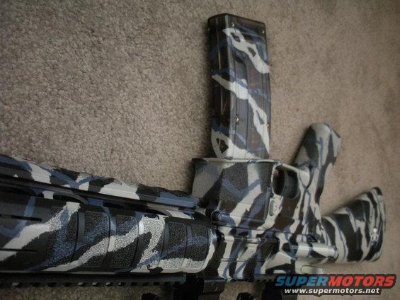 Close-up of a rifle receiver and magazine with a blue, black, and white camouflage pattern