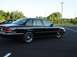 1996 Ford Crown Victoria - A black 1996 Ford Crown Victoria is parked in an empty lot with trees in the background.
