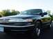 1996 Ford Crown Victoria - A black Ford Crown Victoria is shown from the front quarter angle with a clear sky and trees in the background.