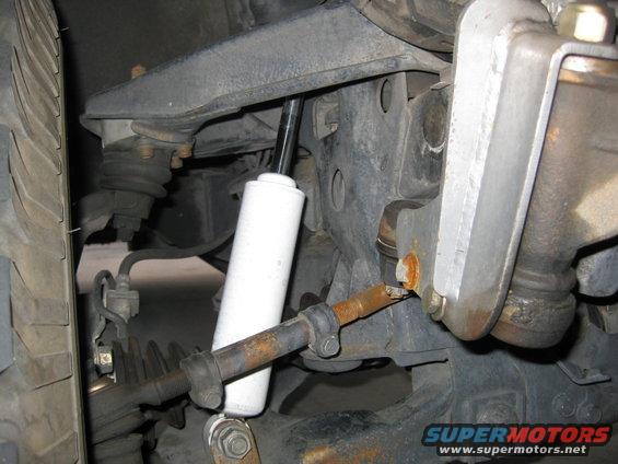 close-up of vehicle's front suspension, showing shock absorber, tie rod, and steering linkage