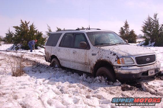 White 2002 Ford Expedition stuck in snow and mud, front 3/4 view