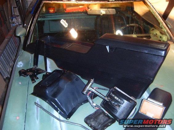 Car interior parts including a center console and shifter assembly laid out on a car's dashboard